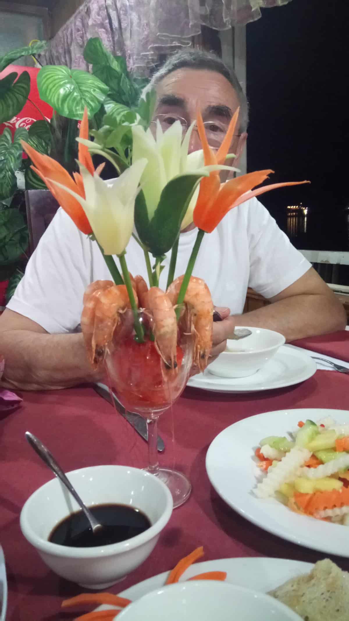 My Halong Bay Cruise Experience in Vietnam 6 Enjoying fresh shrimp on our Halong Bay cruise with one of our fellow cruise passengers eating dinner in the background