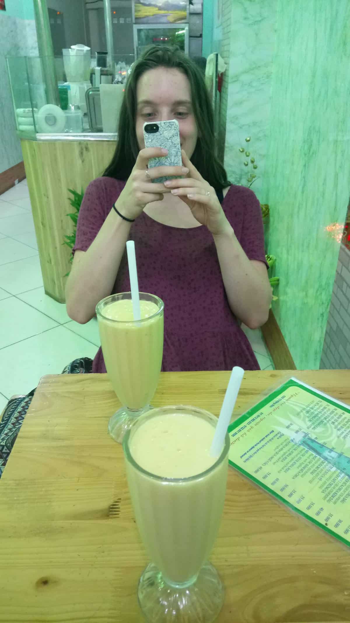 The Best Things to Do in Hanoi, Vietnam 4 Emilie taking a photo of us enjoying smoothies in Vietnam