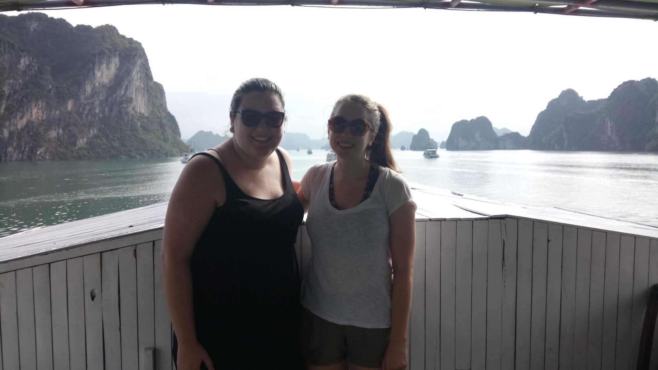 My Halong Bay Cruise Experience in Vietnam 11 Riana and Emilie smiling on the back of their Halong Bay Cruise with limestone cliffs and water behind them
