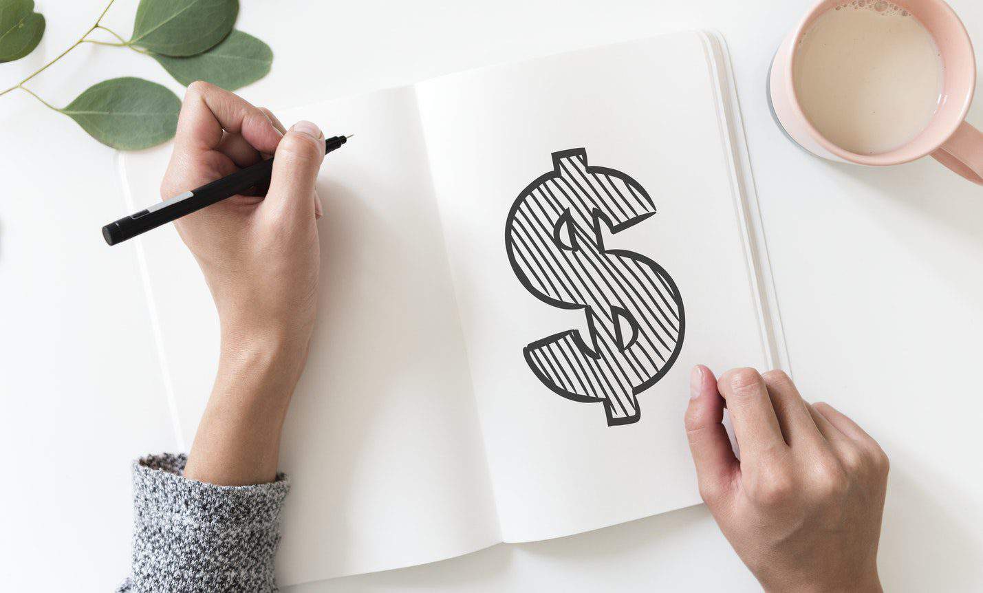 7 Tips for Managing Finances as a Couple 4 Hand drawing a dollar sign on a notebook