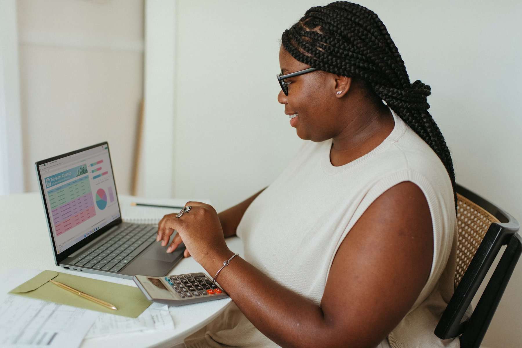 7 Tips for Managing Finances as a Couple 3 Woman smiling at her laptop as she makes a budget spreadsheet ahead of a money meeting about relationship finances