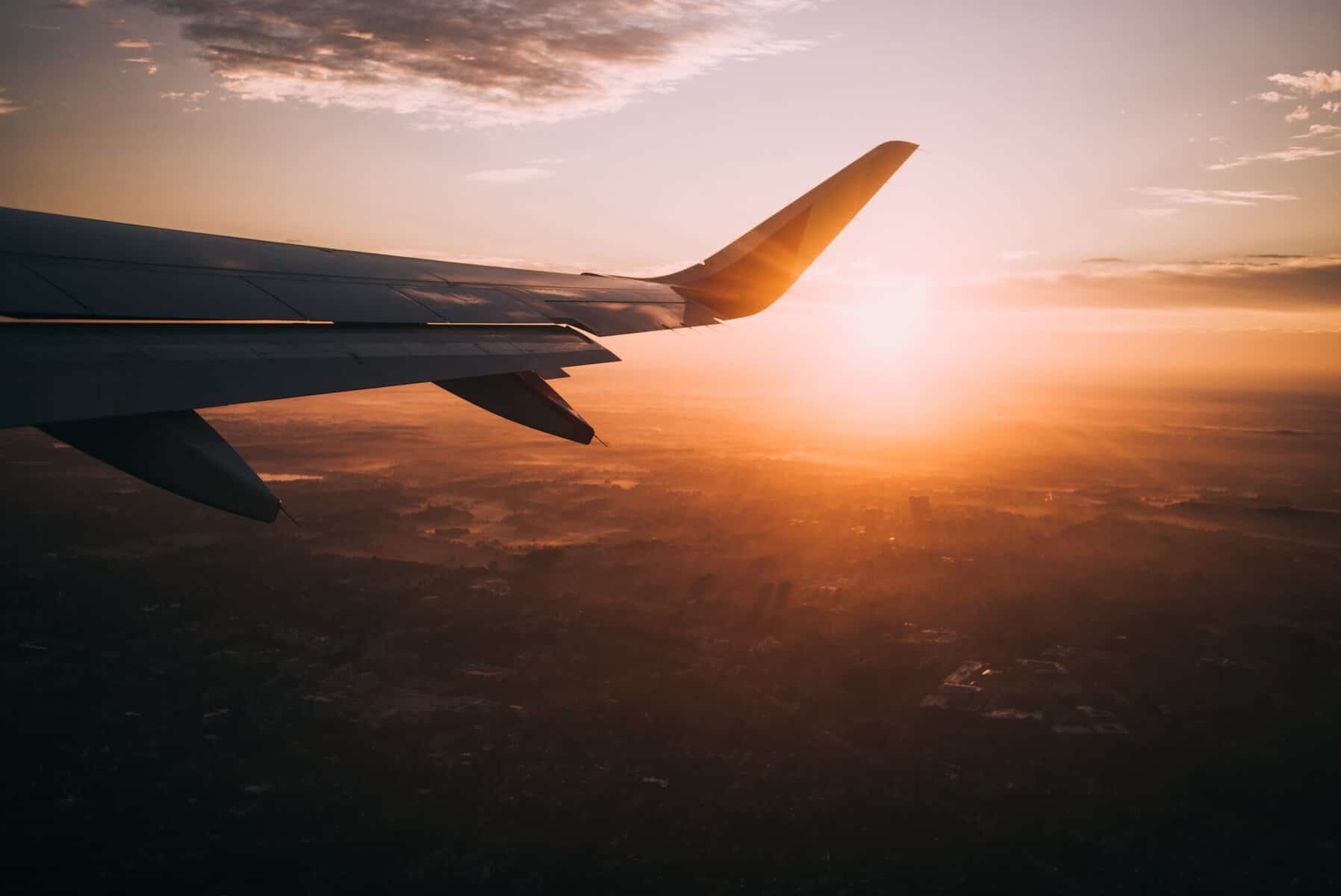 Insane Flight Deals: How to Find the Cheapest Flights to Anywhere! 2 plane wing with sunburst and clouds in the background