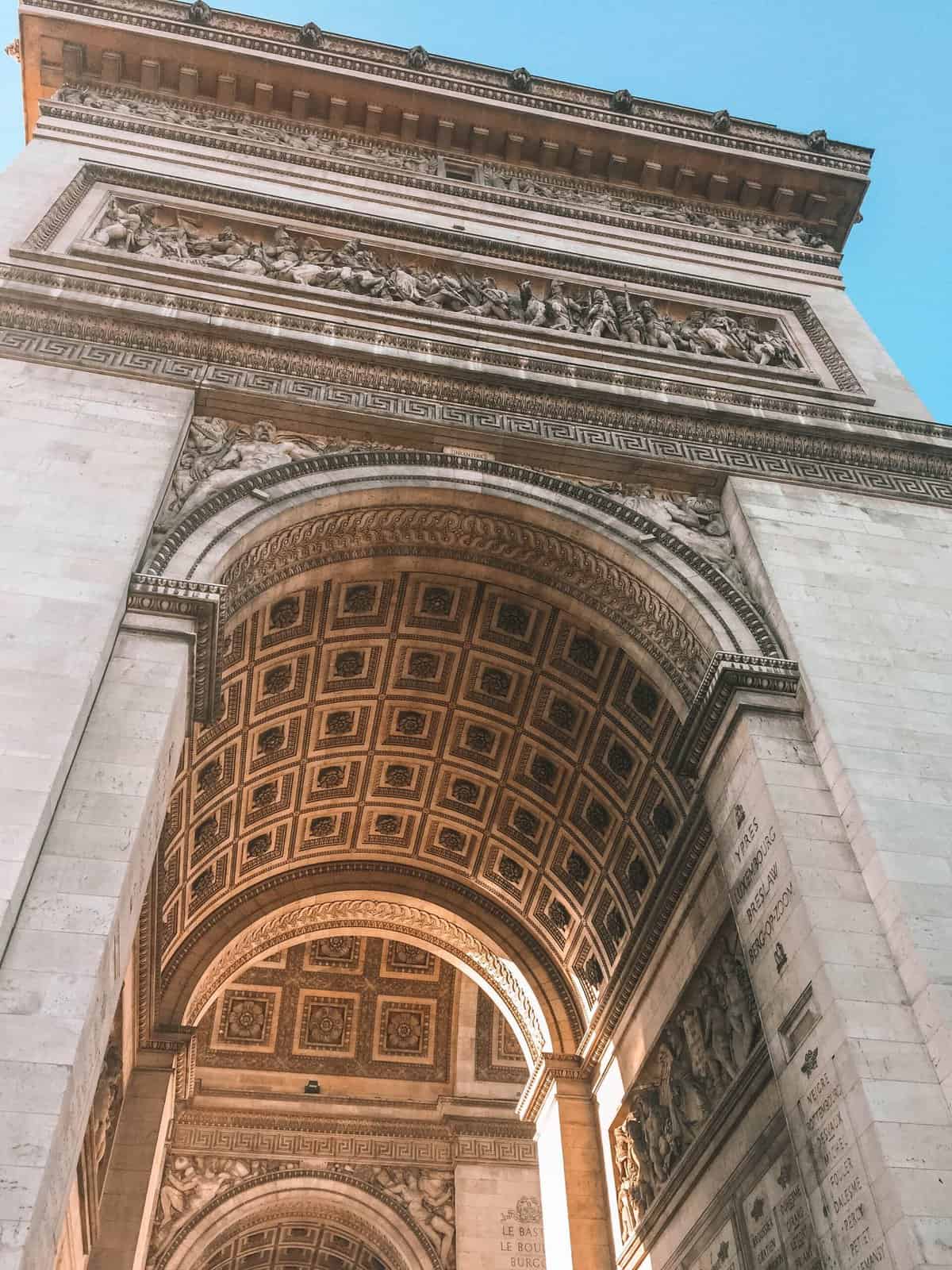 View of the Arc de Triomphe in Paris from the ground, looking up at the design on the underside of the arch
