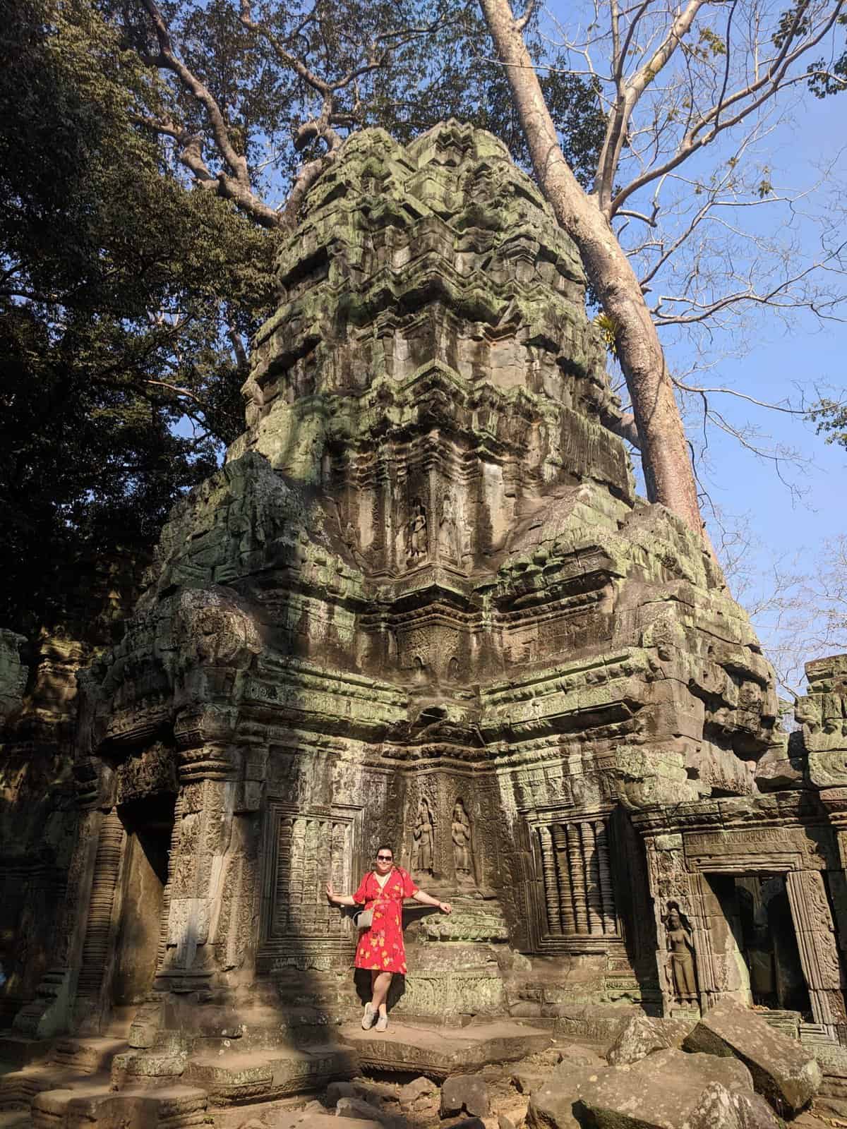 Riana standing in front of a large green temple at Angkor Wat, Cambodia in 2019