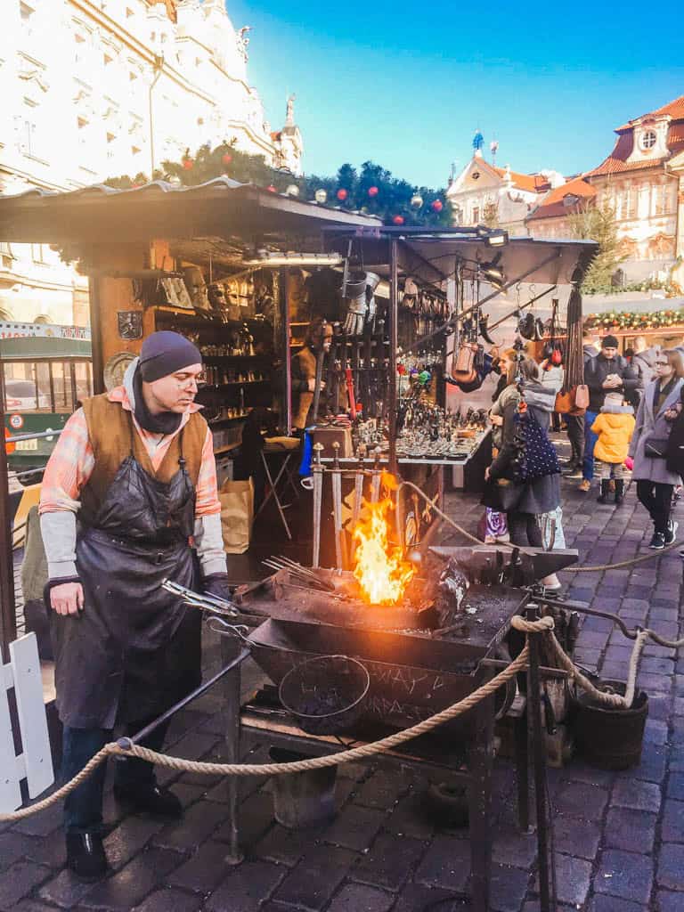 The Ultimate European Christmas Market Road Trip 11 Man working over a fire kiln at the Old Town Square Christmas Market in Prague