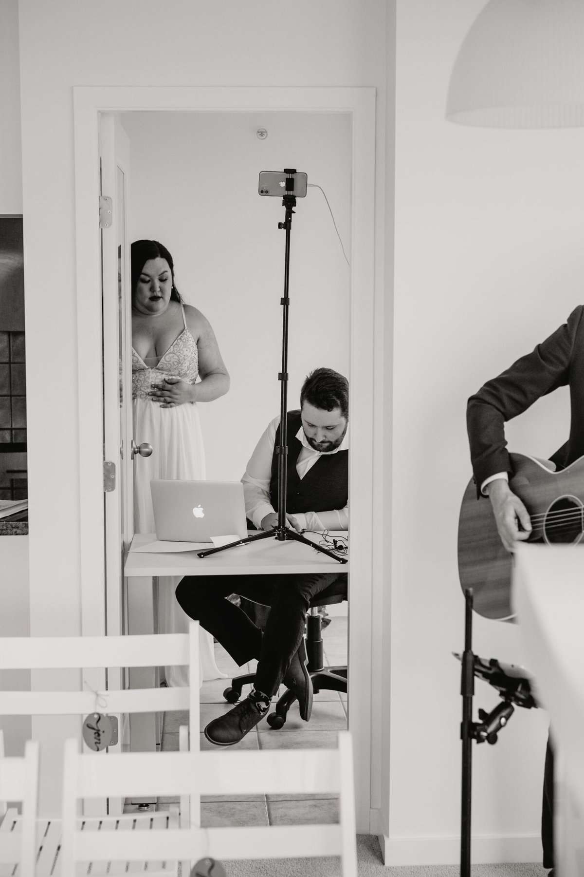 Which Wedding Traditions Did We Actually End Up Skipping? 3 Black and white photo of Riana and Colin setting up their live stream zoom wedding ceremony