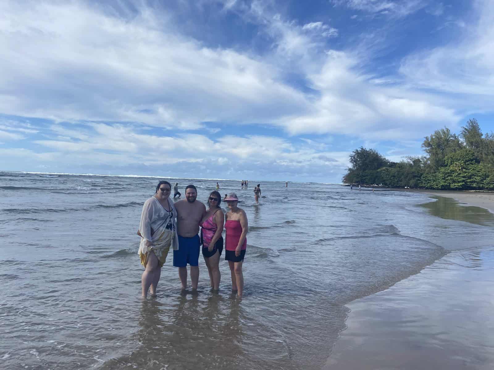 Should You Travel Internationally During COVID? Visiting Hawaii in 2022 2 should you travel during covid? posing with family on Hanalei Beach in Kauai, Hawaii