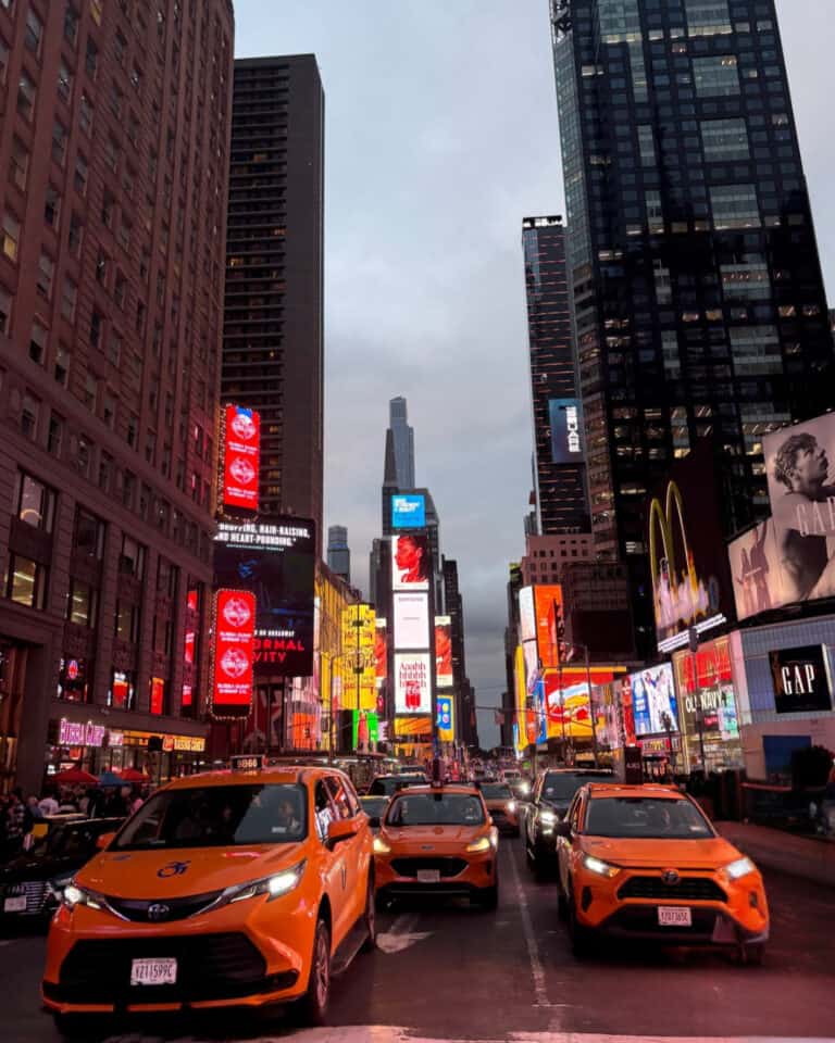 Street in Midtown Manhattan with yellow taxi cabs and lights of Times Square in the background, New York City