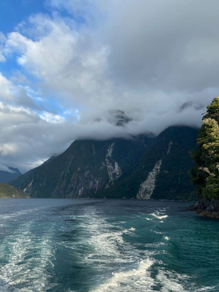 The Ultimate 10 Day New Zealand South Island Itinerary 9 clouds coming over the mountains and water during a cruise in Milford Sound, NZ