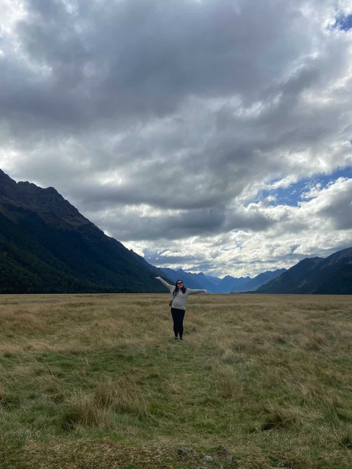 Riana posing in the middle of the Eglinton Valley, drive from Queenstown to Milford Sound, New Zealand
