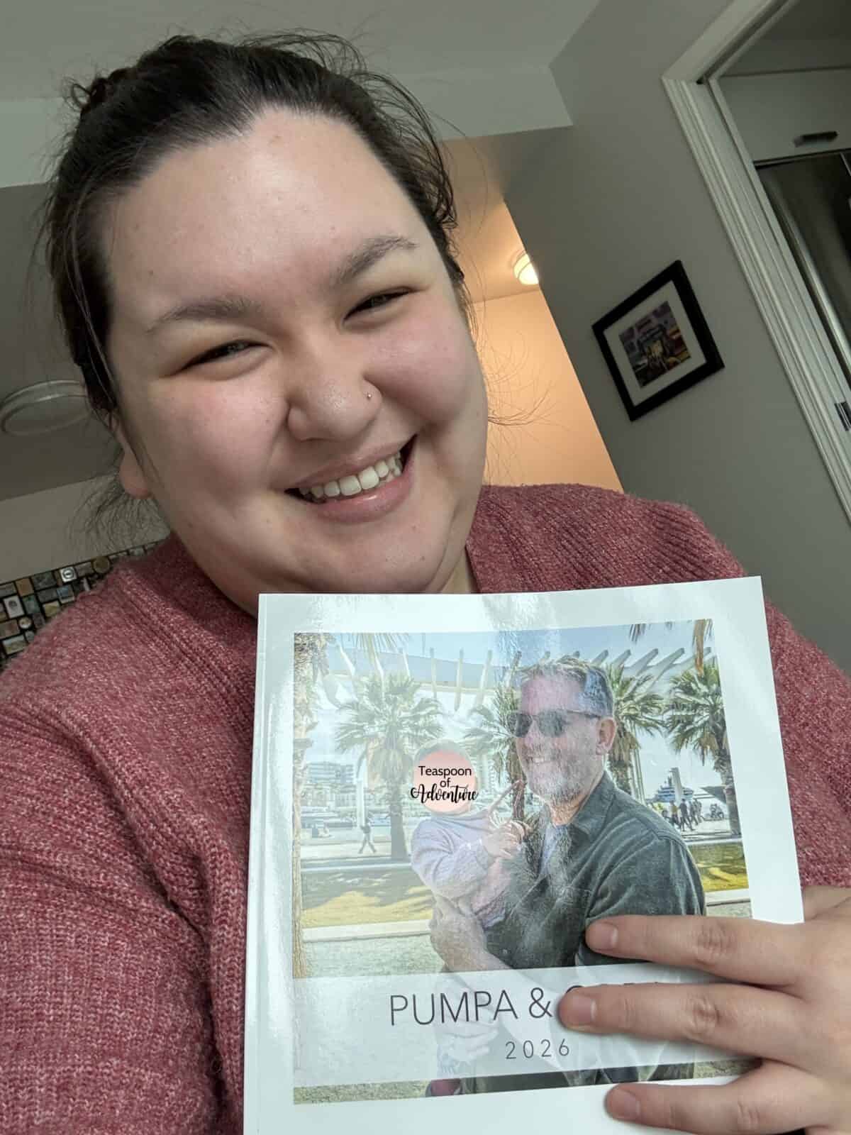 Riana taking a selfie with a Mixbook photo album she created for her dad's birthday using Story Mode