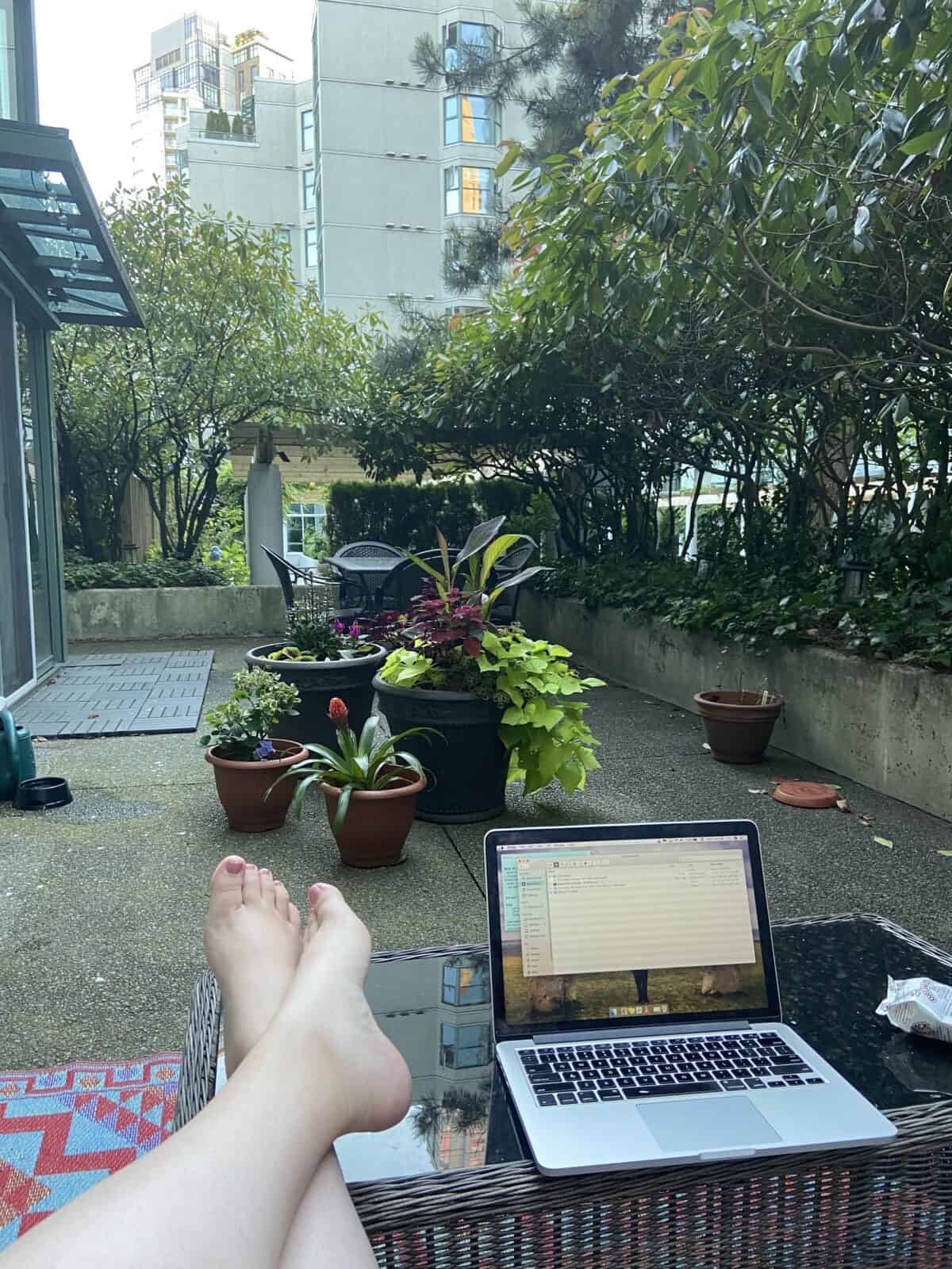 18 Freelancer Tips for Beginners (From an 8 Year Veteran!) 9 Working from the balcony with my legs crossed up on the coffee table, laptop in front of me and looking out at our plants and patio table
