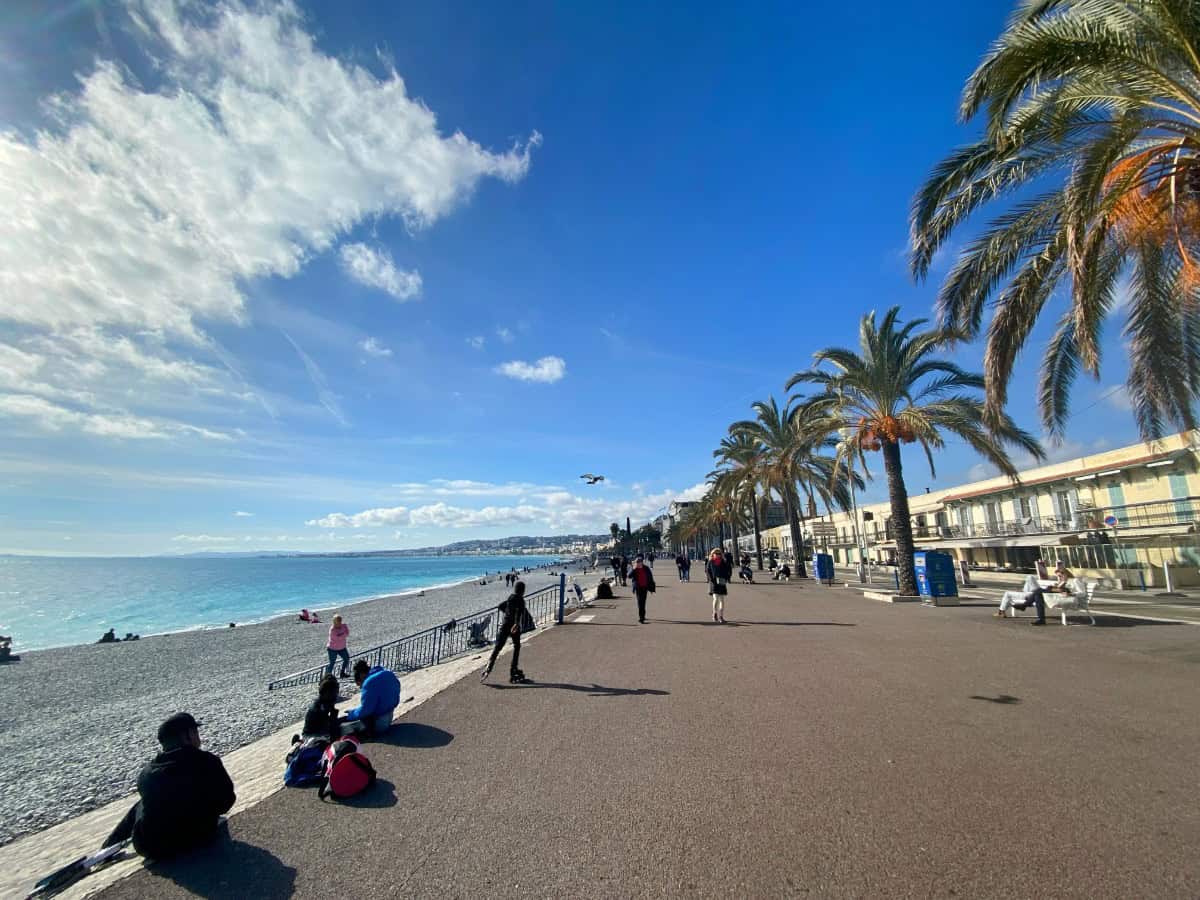 Promenade des Anglais in Nice, France with palm trees and people looking out to the water