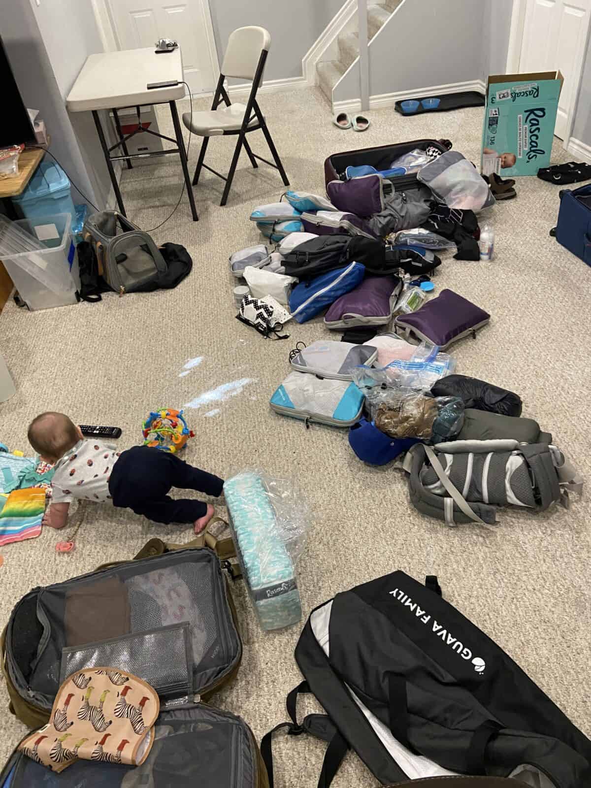Our Essential Packing List for Travel with a Baby 11 Sorting through all of our bags and baby trip packing items on the basement floor in Toronto with Baby C crawling in the distance