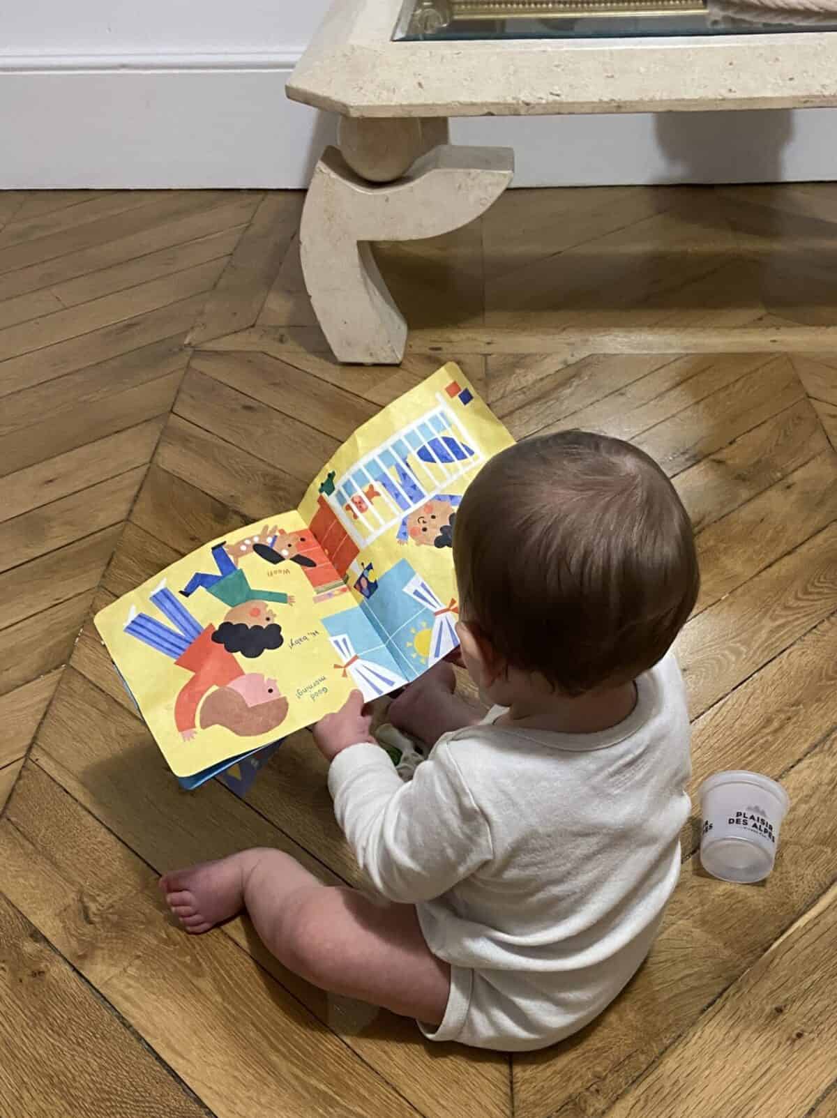Our Essential Packing List for Travel with a Baby 31 Baby C reading one of her travel books upside down with yogurt cups beside her