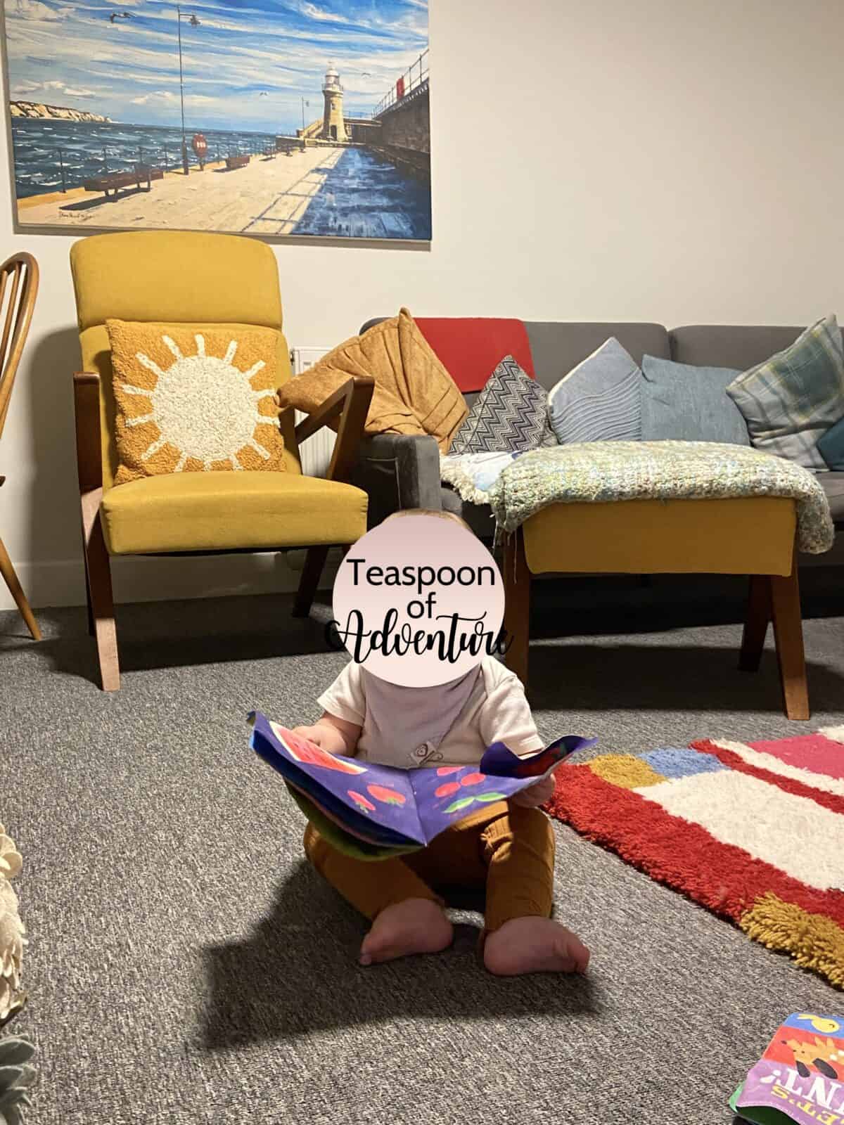 Our Essential Packing List for Travel with a Baby 30 Baby C reading her Indestructible Book on the carpet in Folkestone