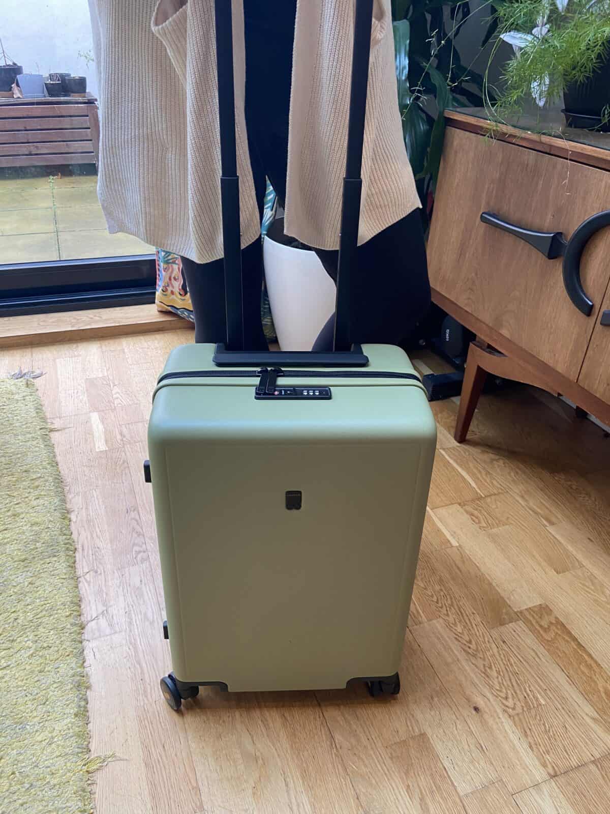 Our Essential Packing List for Travel with a Baby 4 LEVEL8 Luminous Textured 20" carry-on bag in olive green being held by Riana