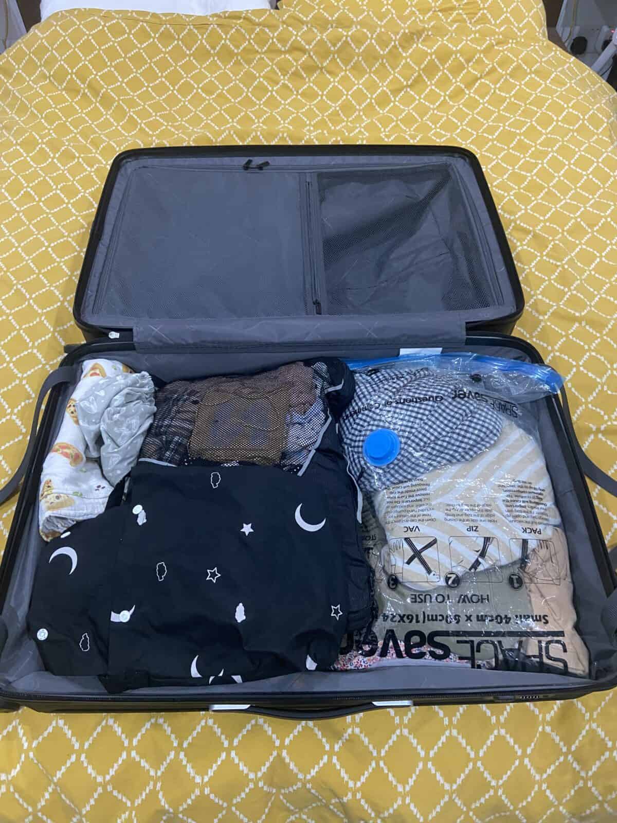 Our Essential Packing List for Travel with a Baby 41 Baby clothing, blackout blind, sheets and blankets packed into a LEVEL8 Grace checked in suitcase