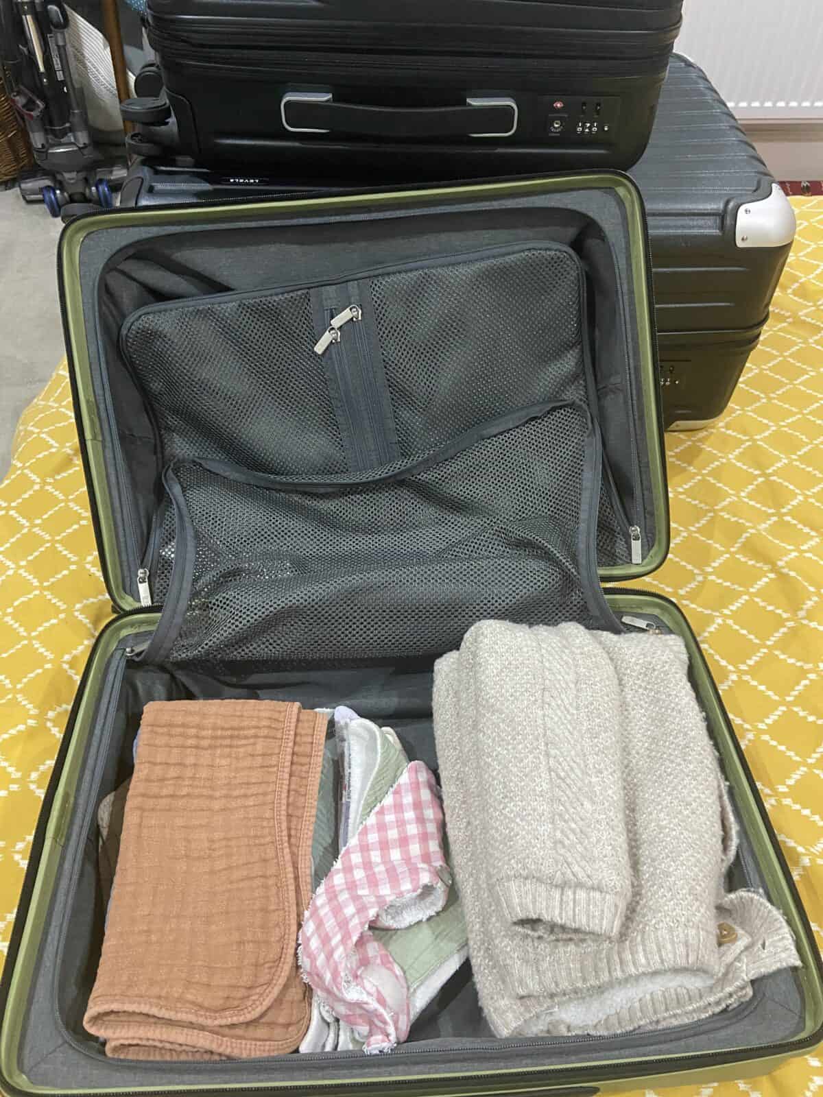 Our Essential Packing List for Travel with a Baby 38 Burp cloths, bibs and a large baby sweater packed into the the Luminous Textured Carry-On 20" LEVEL8 carry on suitcase