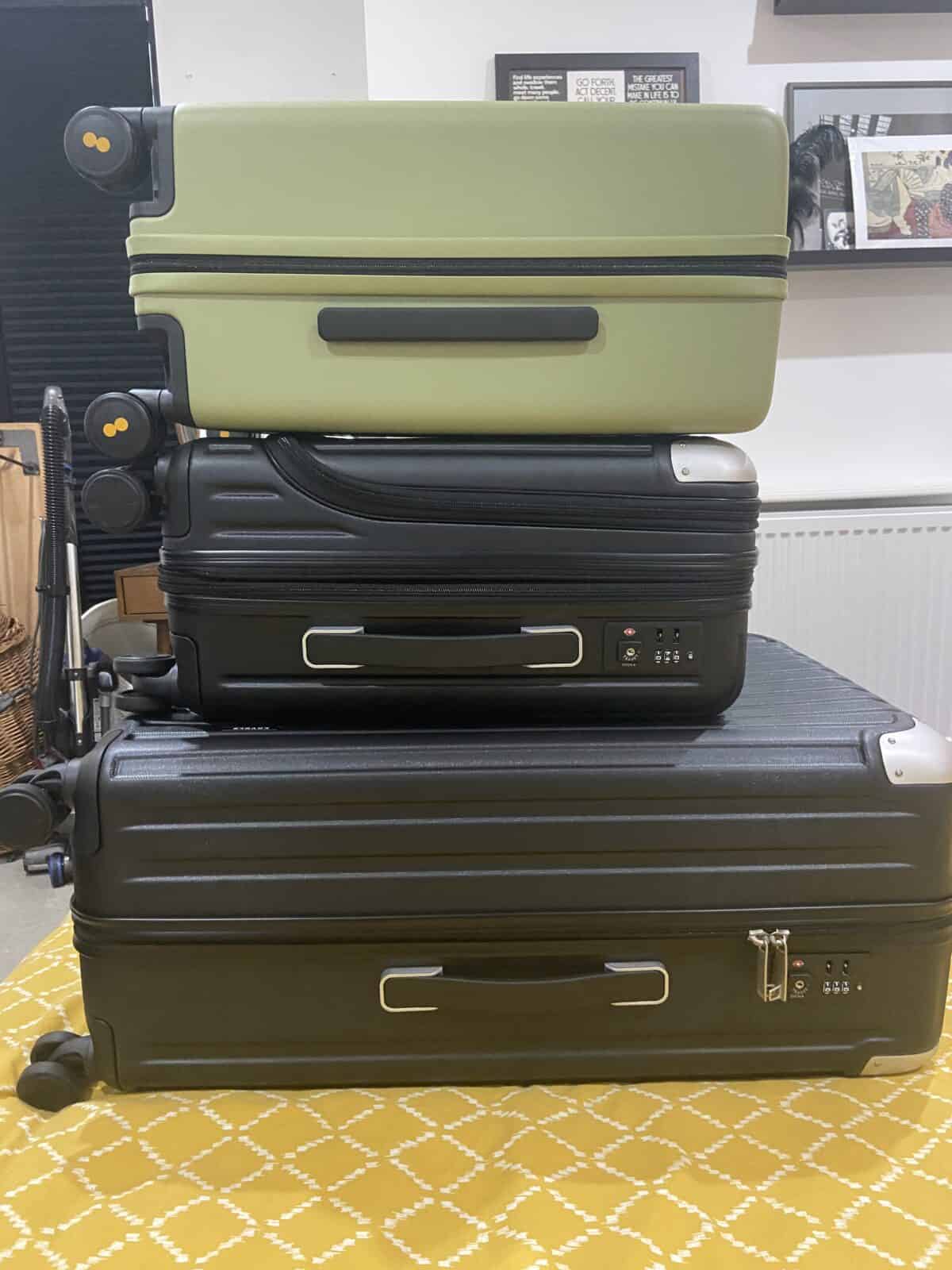 Our Essential Packing List for Travel with a Baby 3 Three LEVEL8 suitcases piled on top of each other on a yellow bedspread