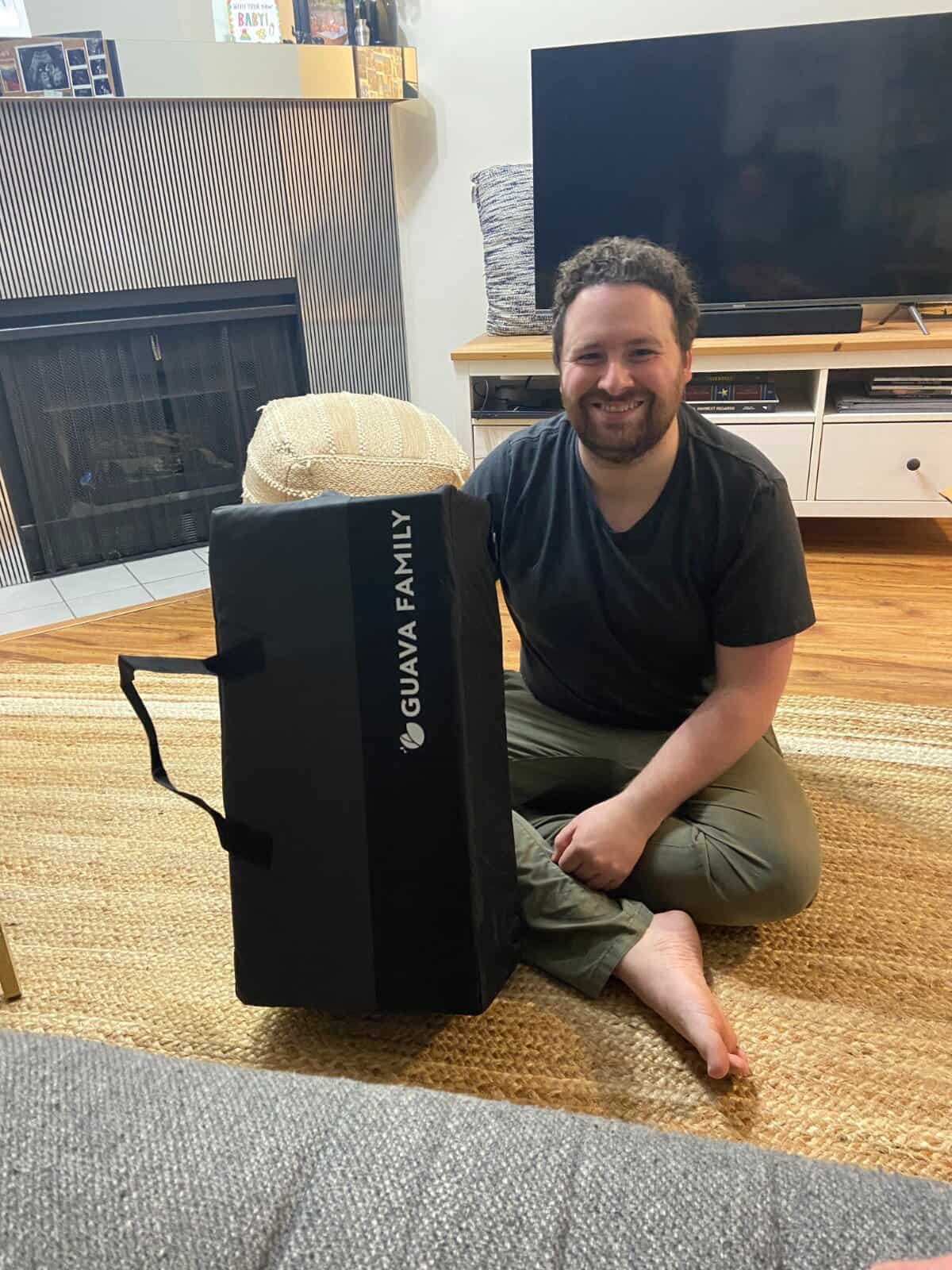 Our Essential Packing List for Travel with a Baby 33 Colin sitting with the Guava Family Travel Crib in its carrying case