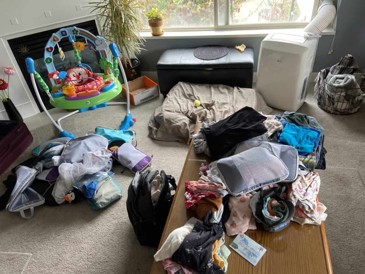 Our Essential Packing List for Travel with a Baby 12 Sorting through all of our stuff and deciding what to include on our Packing List for Travel with a Baby with bags and clothing piles spread out in the living room