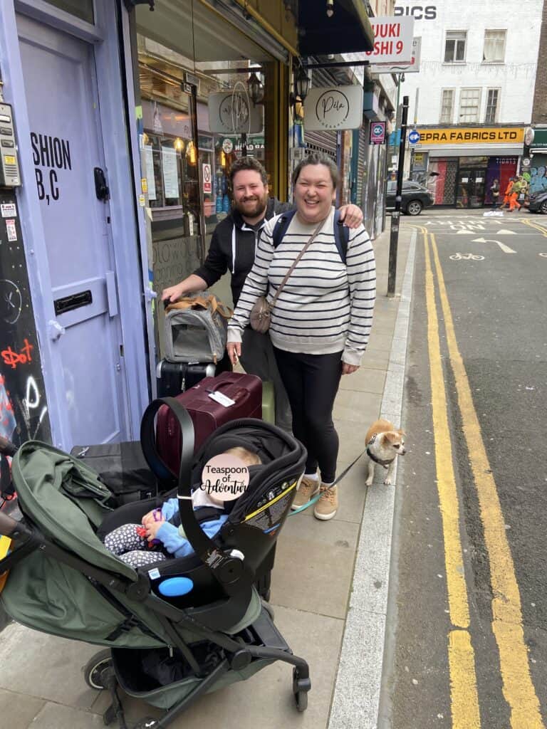 Riana, Colin, Baby C and Ellie stand with all of their bags in front of their London Spitalfields apartment on the last day of their Baby Trip