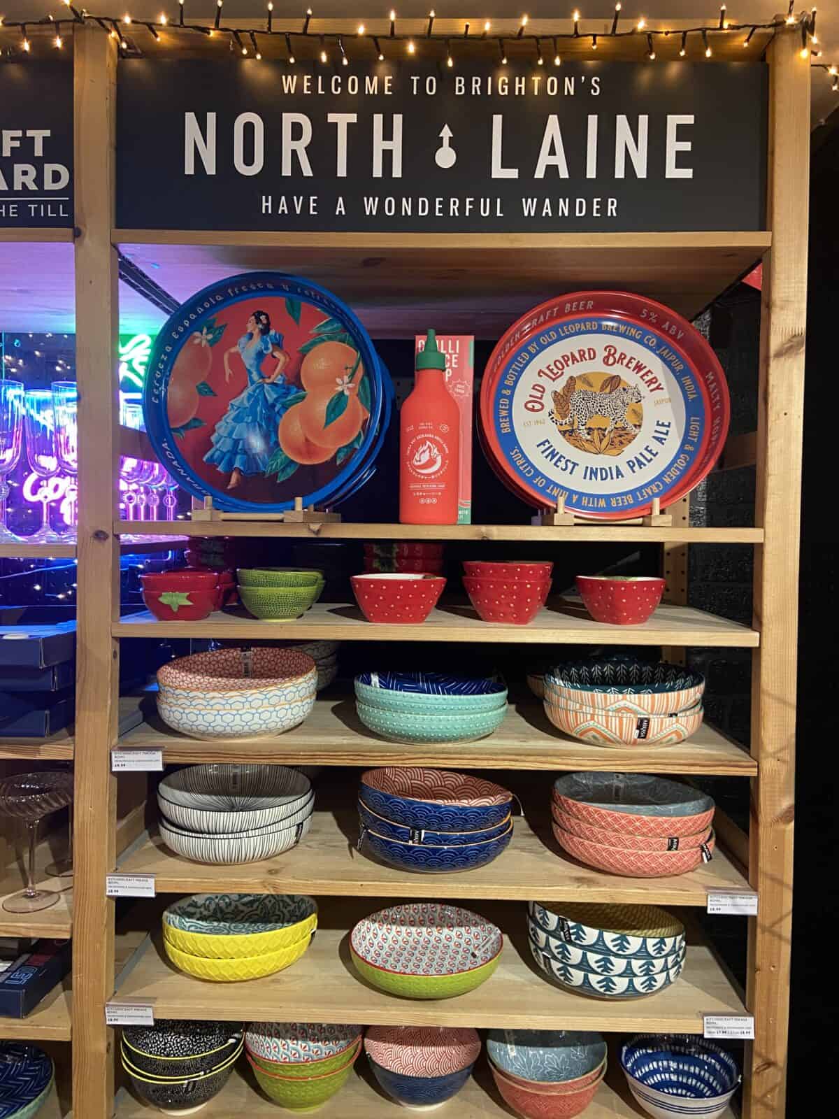 Your Guide to Brighton's North Laine 15 A shelf displaying plates and bowls under a sign that says welcome to North Laine in Bert's Home Store in Brighton