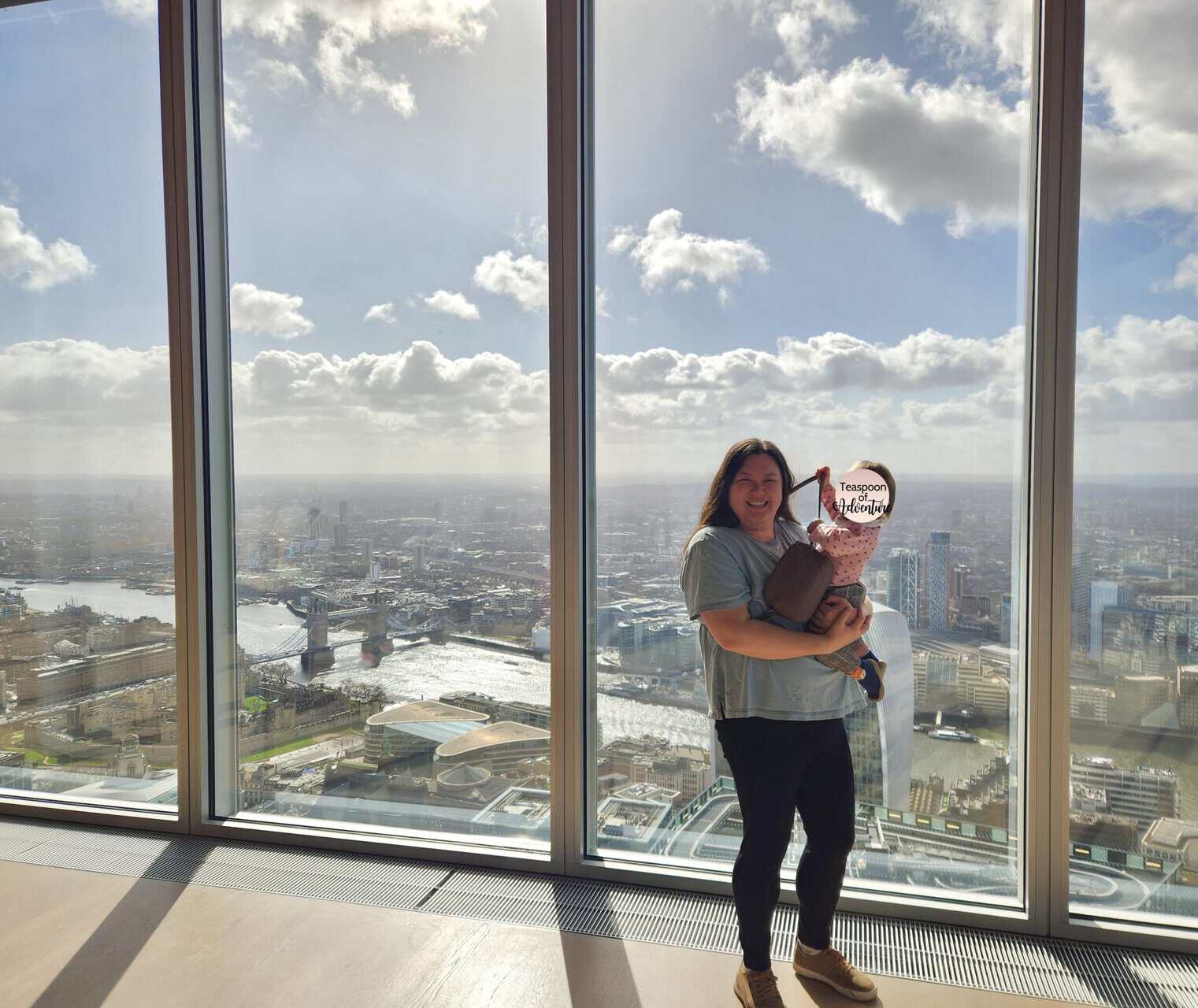 20+ Things to Do in London With a Baby 29 Riana and Baby C standing next to the glass at The Lookout with a view of Tower Bridge behind them, London, UK