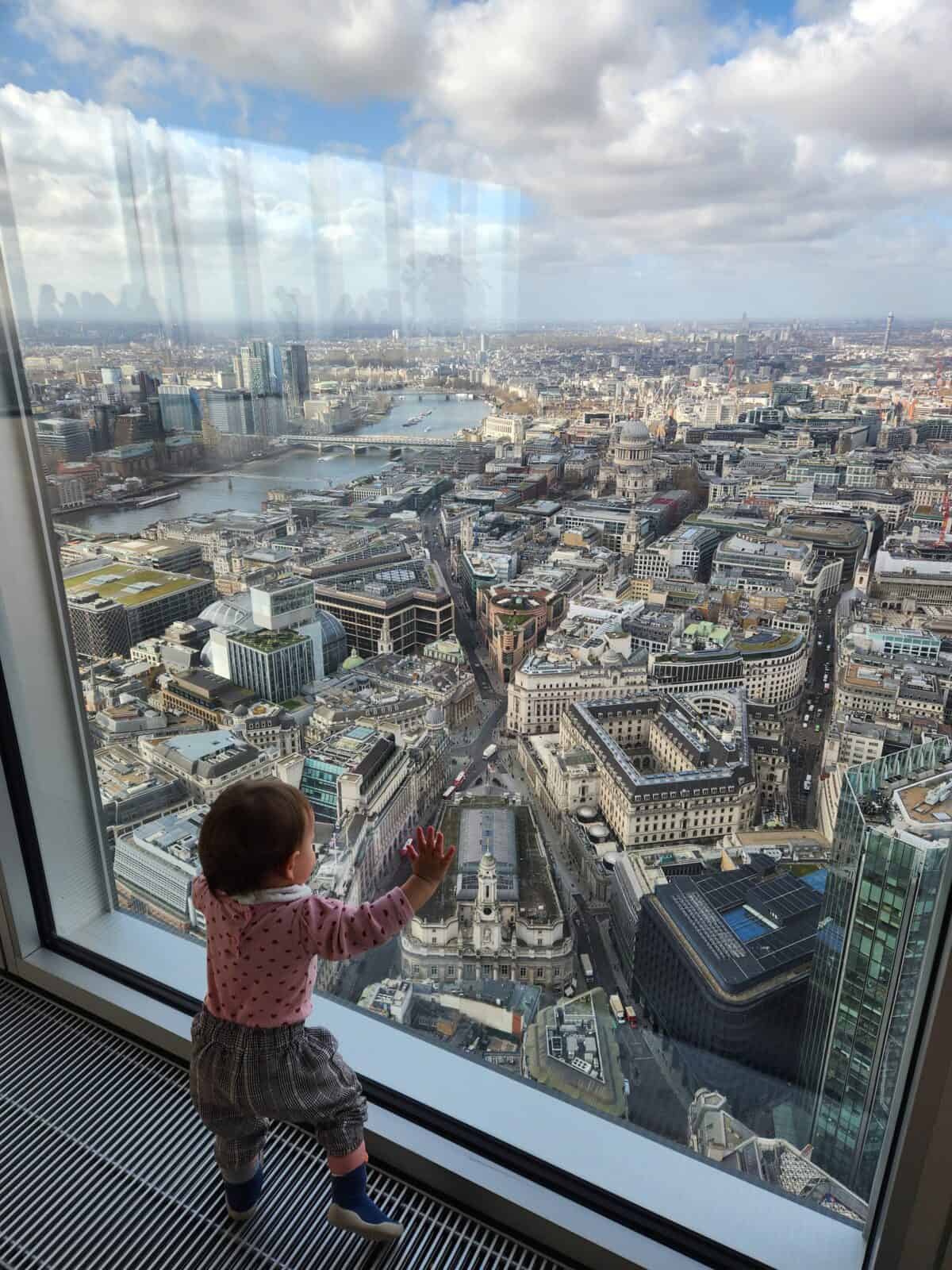 20+ Things to Do in London With a Baby 30 Baby C standing against the window and looking at the London skyline from The Lookout viewpoint