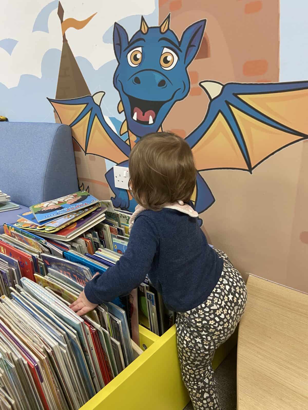 20+ Things to Do in London With a Baby 20 Baby C reaching for books in front of a dragon mural in the kids' section of Artizan Street Library in Spitalfields, London