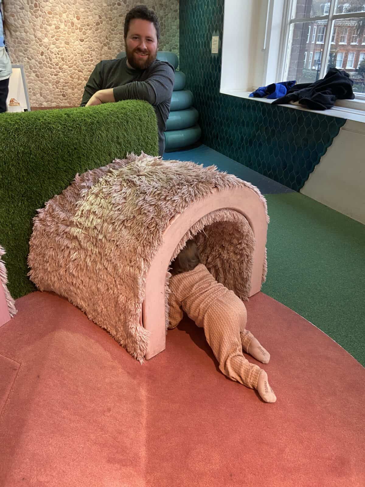 20+ Things to Do in London With a Baby 14 Baby C in the 0-2 year old room at Young V&A children's museum in London. She's crawling through a pink fuzzy tunnel and Colin is smiling on the other side.