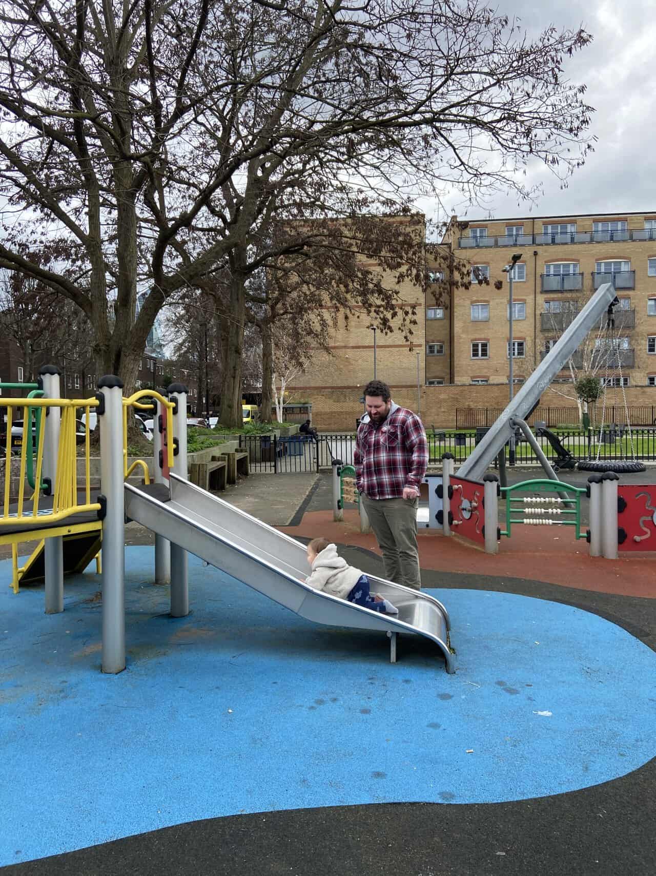 20+ Things to Do in London With a Baby 41 Baby C and Colin at a playground in Spitalfields, one of the easiest things to do in London with a baby. Baby C is crawling up the slide while Colin watches.