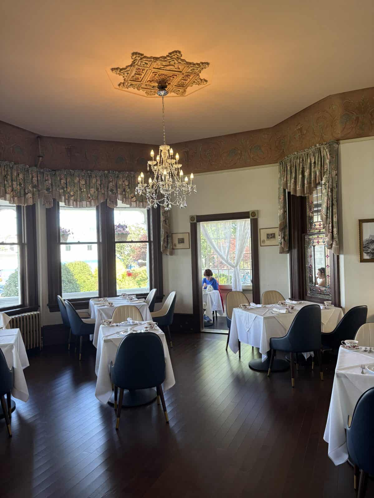 Pendray Tea House Review: Afternoon Tea in Victoria, BC 6 One of the dining rooms at Pendray Tea House in Victoria BC with tables, chairs, a chandelier and tall windows