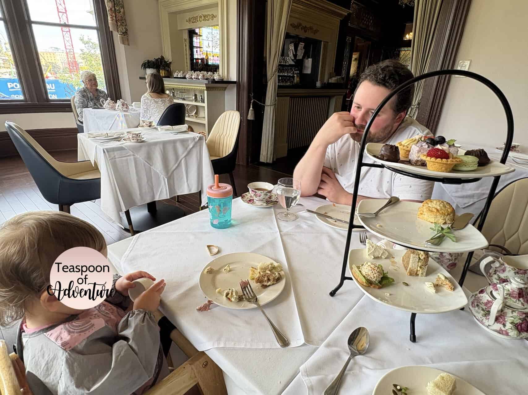 Pendray Tea House Review: Afternoon Tea in Victoria, BC 11 Colin and Baby C seated at a table at Pendray Inn and Tea House in Victoria BC with a three tier stand of food for afternoon tea on the table