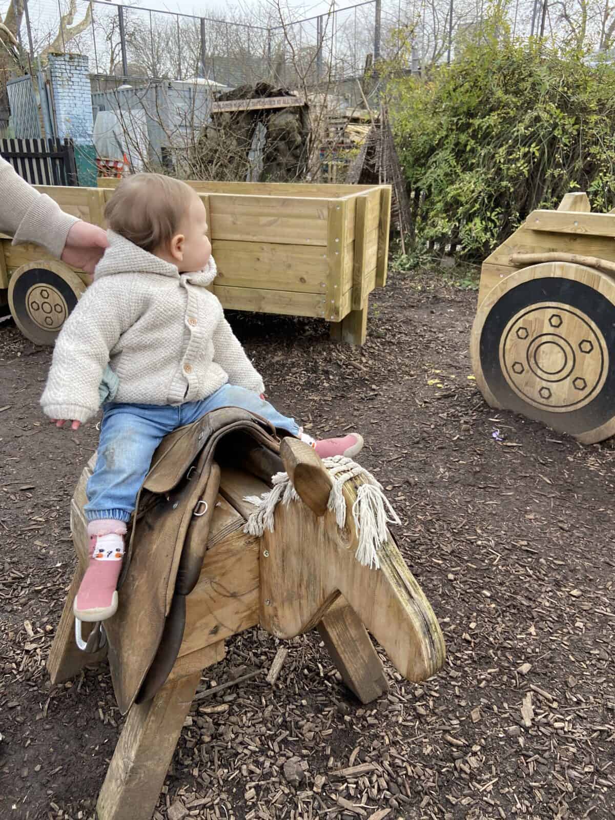 20+ Things to Do in London With a Baby 25 Baby C riding on a wooden horse at the playground area of Spitalfields City Farm in London