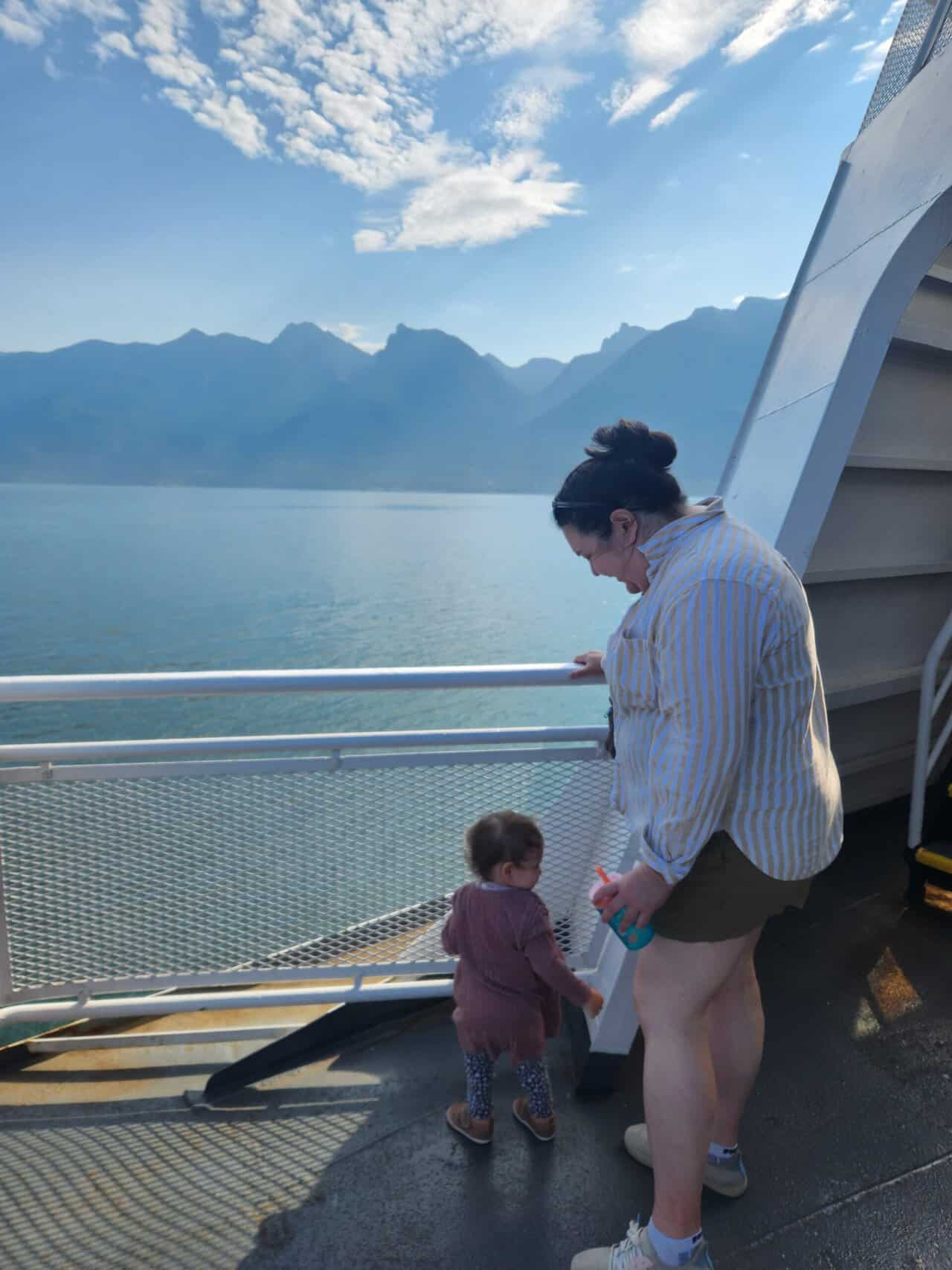 How to Get to Victoria from Vancouver, BC 10 Riana standing on the outer deck of a BC Ferries boat with Baby C and the ocean and mountains behind them