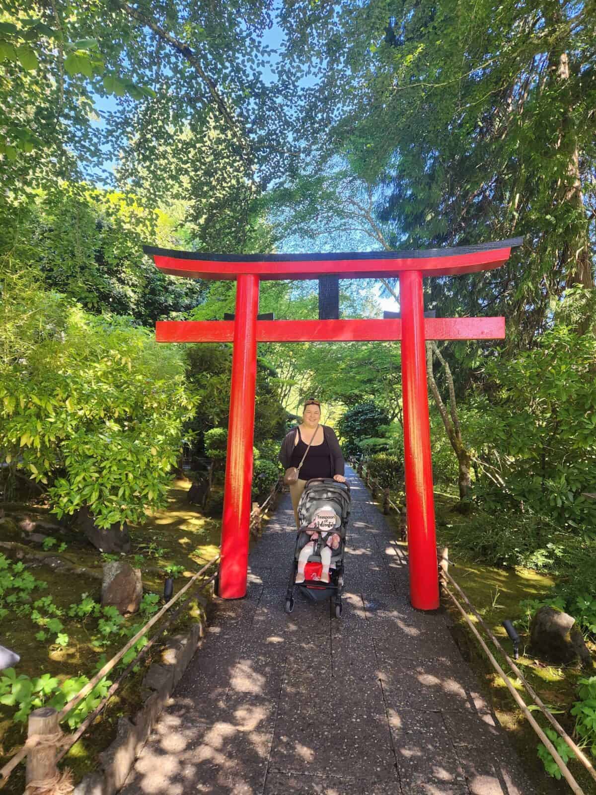 Riana and Baby C at the entrance to the Japanese Garden in front of a red tori gate at Butchart Gardens