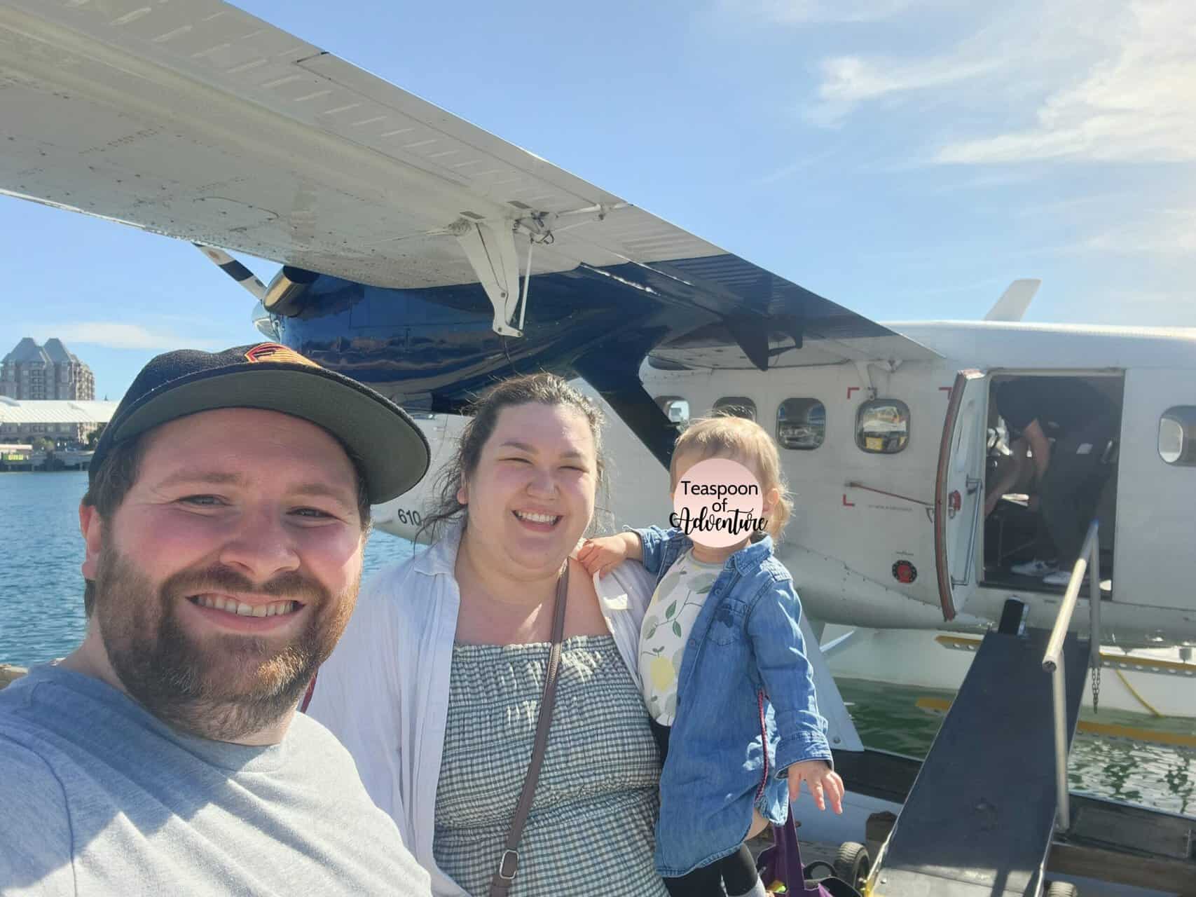 Selfie of Colin, Riana and Baby C in front of a Harbour Air plane, taking the seaplane to Victoria from Vancouver BC