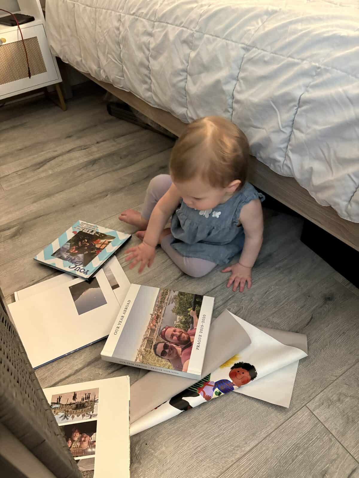Making A Custom Board Book From Our Travel Photos 13 Baby C sitting on the floor with a pile of photo books around her