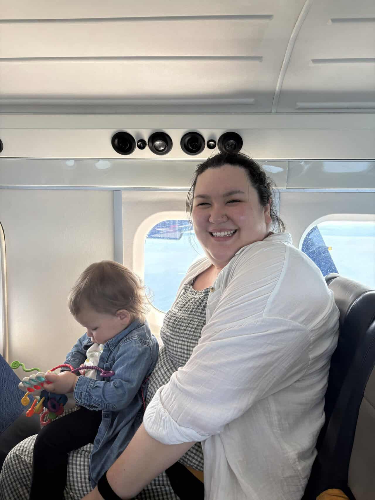 Should You Take a Seaplane to Victoria from Vancouver? (Harbour Air Review) 13 Riana smiling at the camera with Baby C on her lap on board a Harbour Air seaplane to Victoria