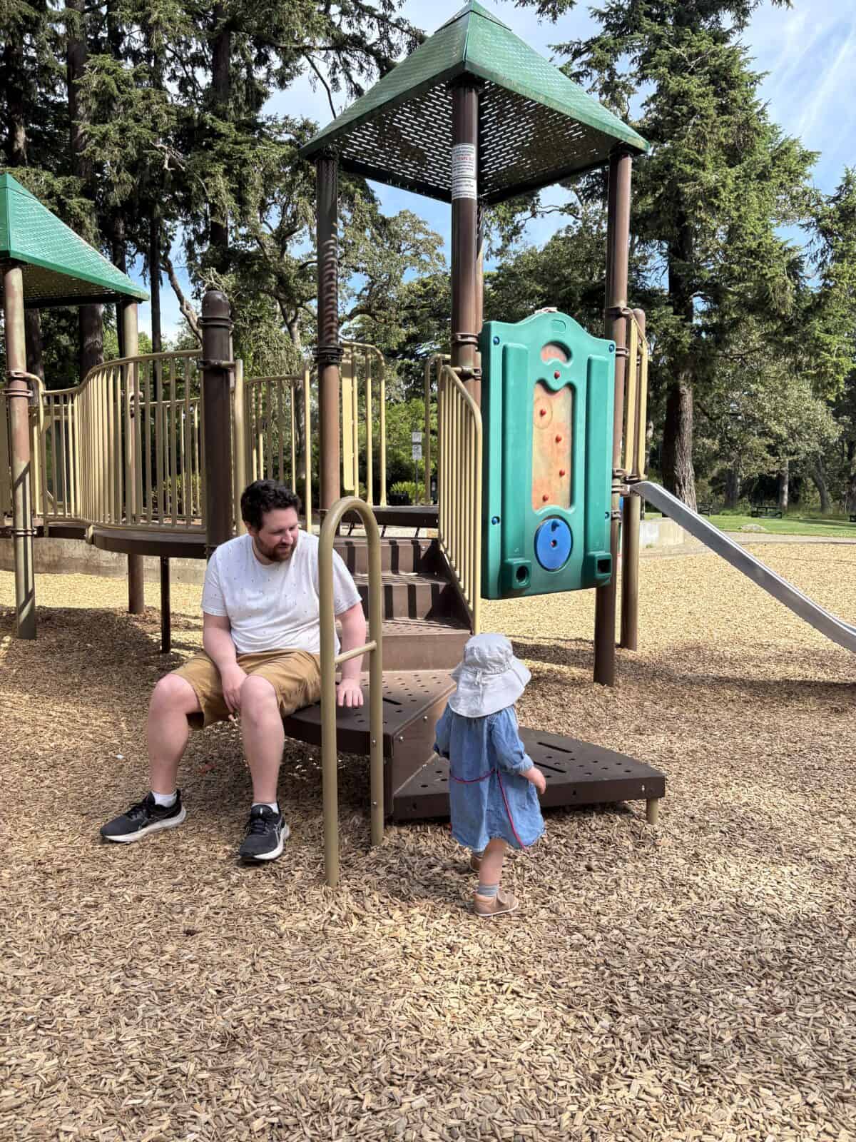 Colin and Baby C sitting on a structure at the Beacon Hill Park North Playground in Victoria, BC