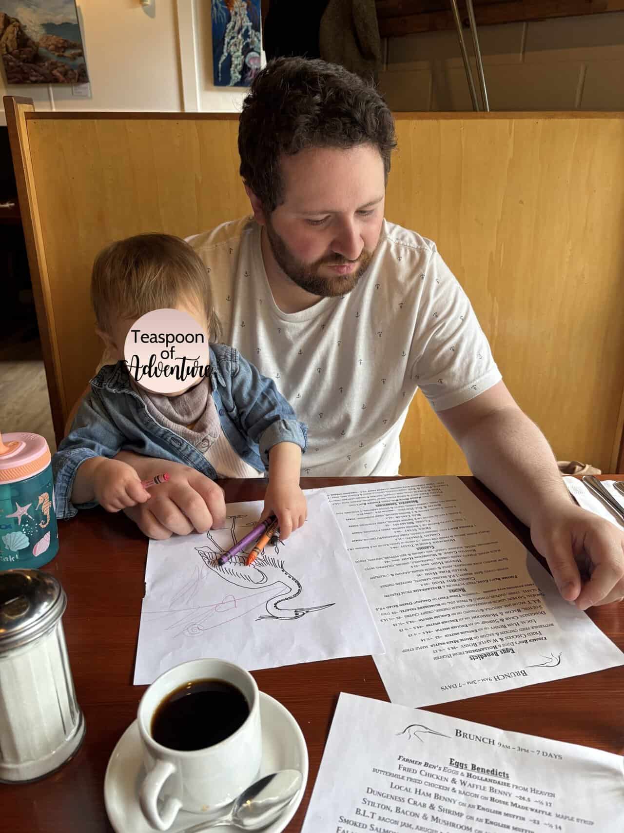 Colin and Baby C studying the menu at Rock Heron Bistro and colouring in the kids menu 