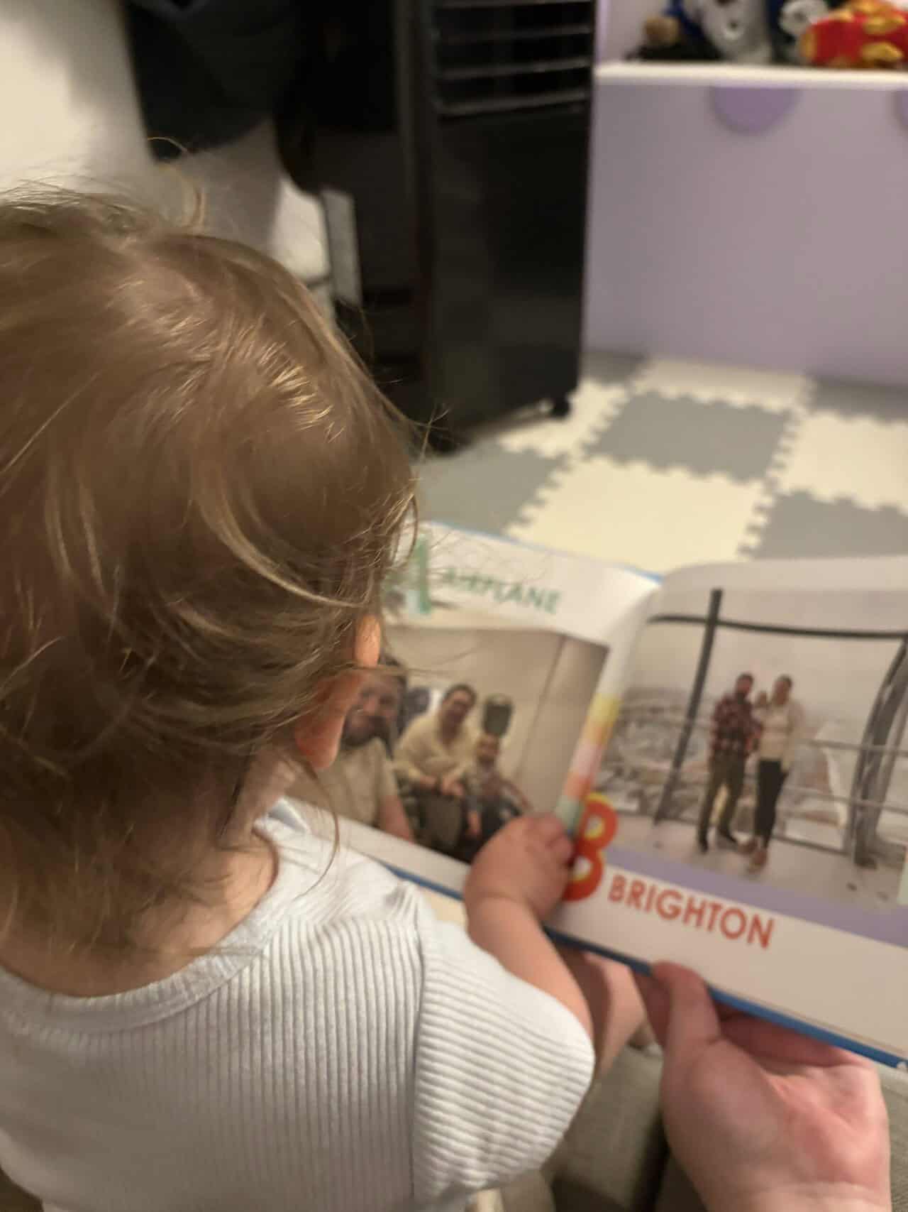 Baby C reading her custom board book with a travel alphabet showing off letters A and B from Mixbook