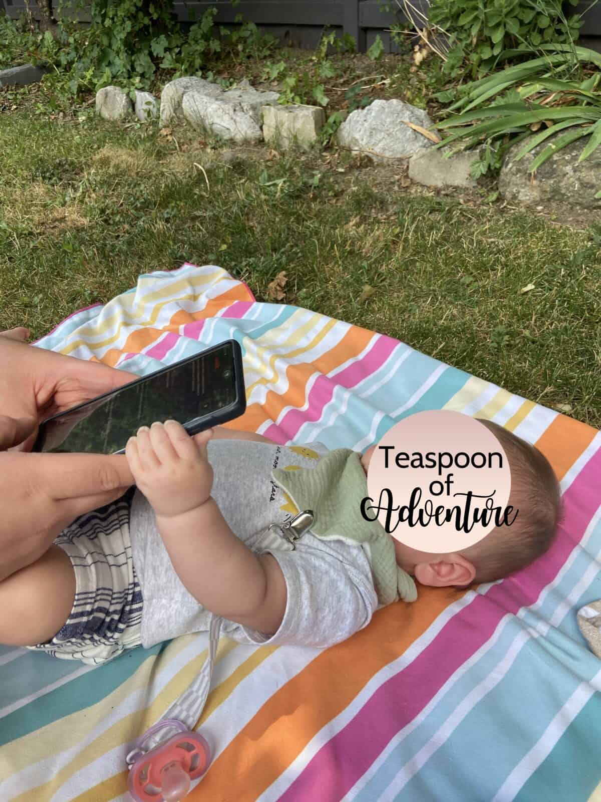 Why an eSIM Is Essential for Family Travel 7 Baby C lying on a blanket holding a cell phone