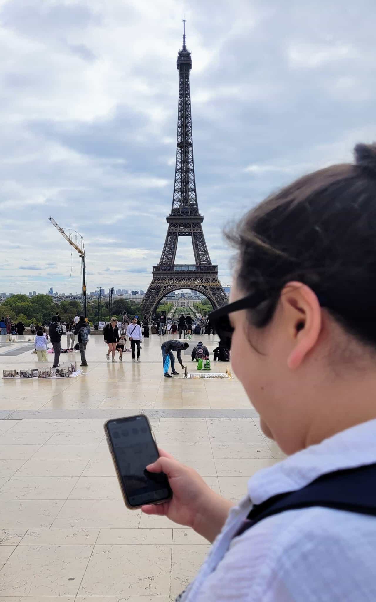 Why an eSIM Is Essential for Family Travel 5 Riana scrolling on her phone in front of the Eiffel Tower
