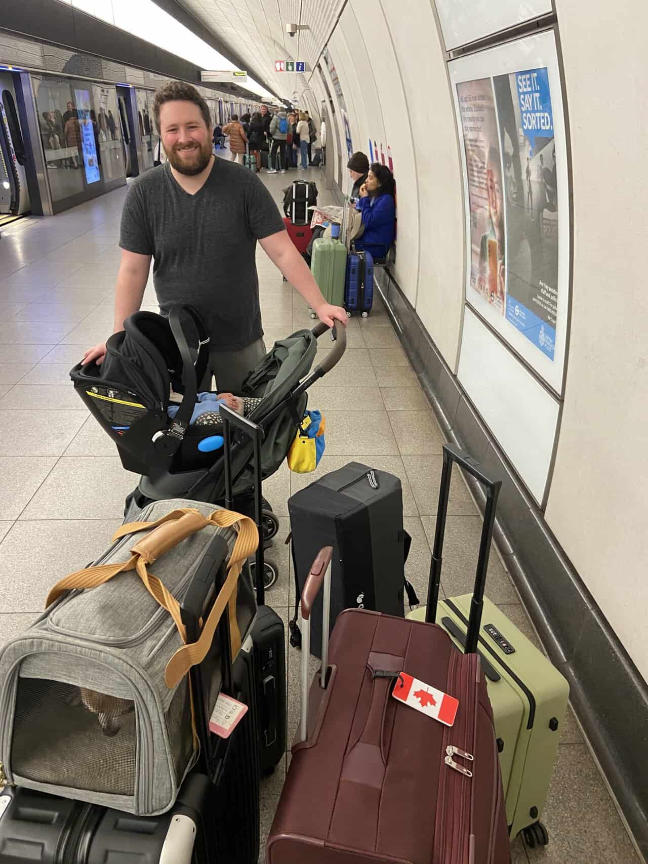 Tips for Flying With a Baby: From Booking to Baggage Claim 10 Colin smiling behind C in her car seat and stroller and all of our luggage