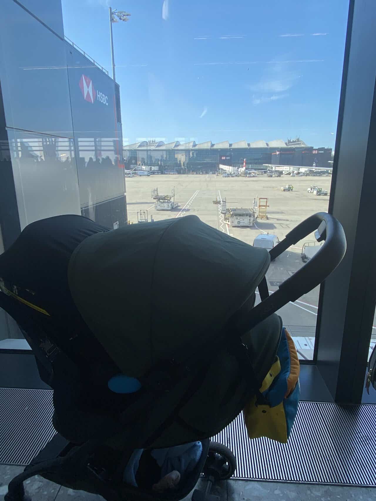 Tips for Flying With a Baby: From Booking to Baggage Claim 14 Baby C in her car seat attached to her stroller waiting at the gate to board an airplane