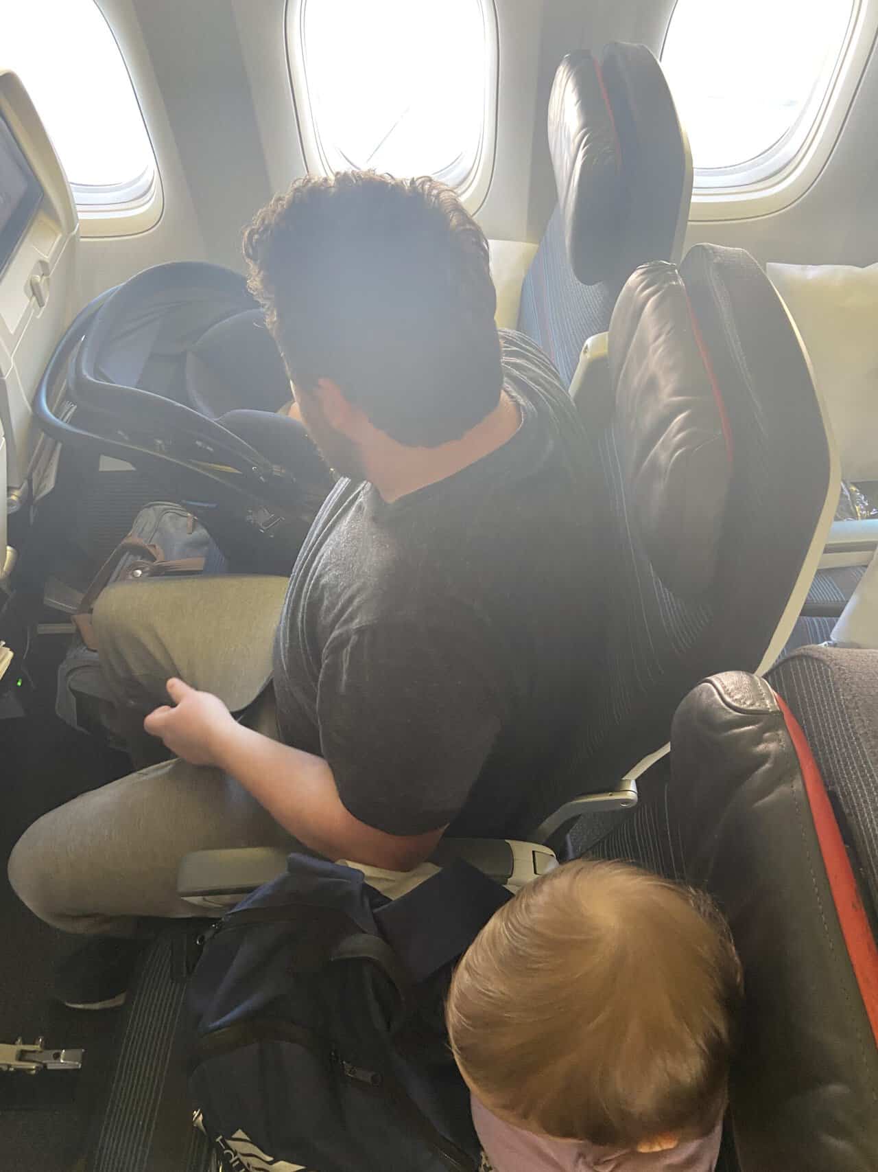 Tips for Flying With a Baby: From Booking to Baggage Claim 35 Colin setting up C's car seat on the plane while she sits in the seat next to him