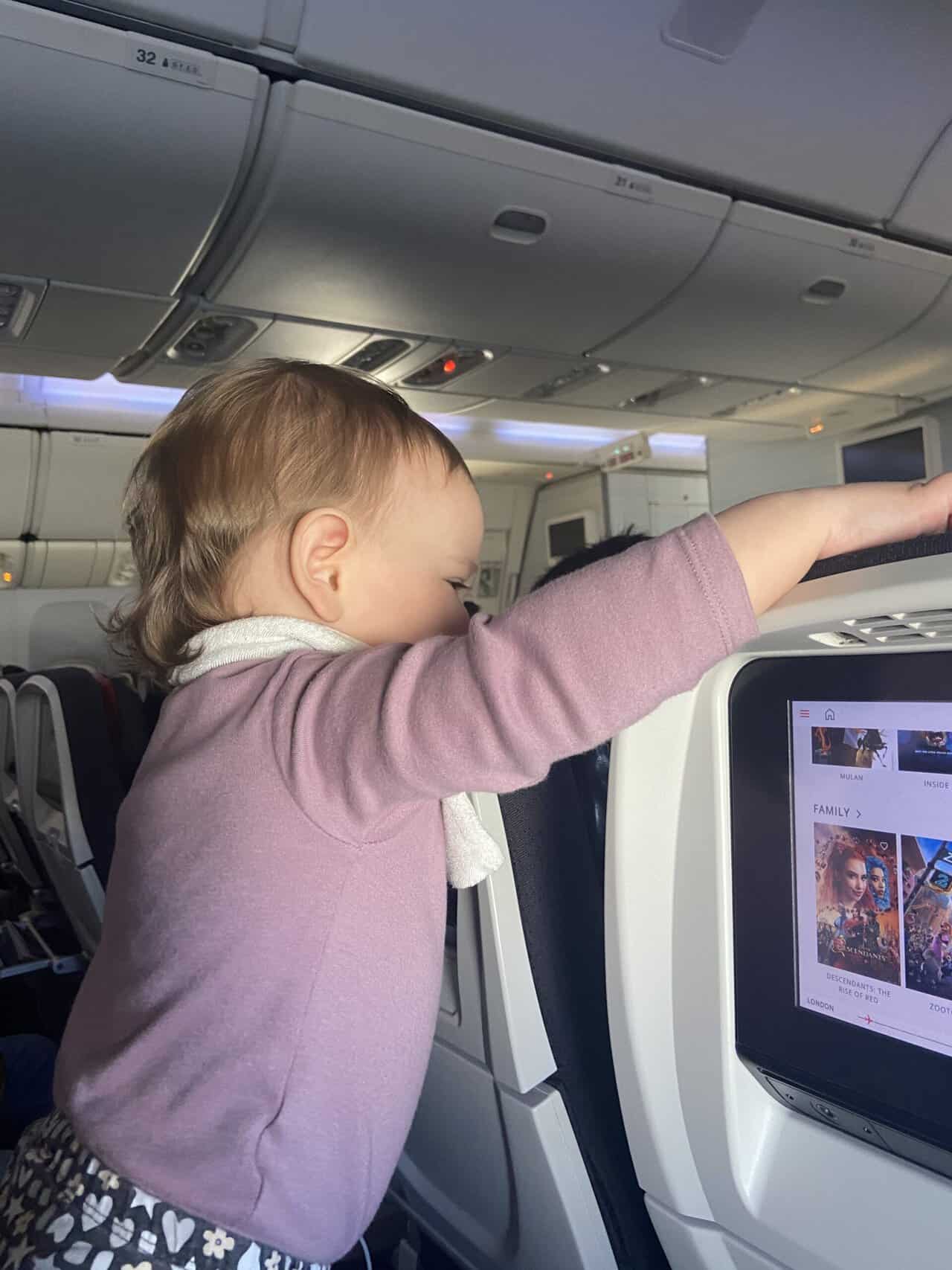 Tips for Flying With a Baby: From Booking to Baggage Claim 2 Baby C reaching over the seats on an airplane to say hi to the people in front of us